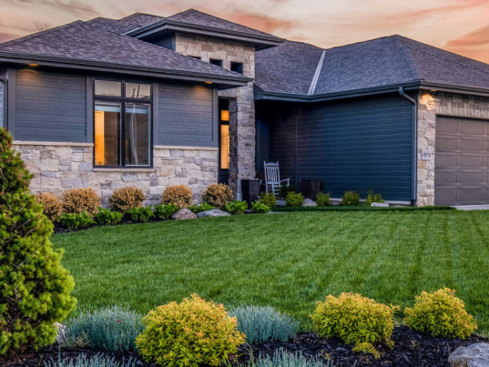 A suburban house with luxurious, minimal landscaping. The sun is setting in the background.