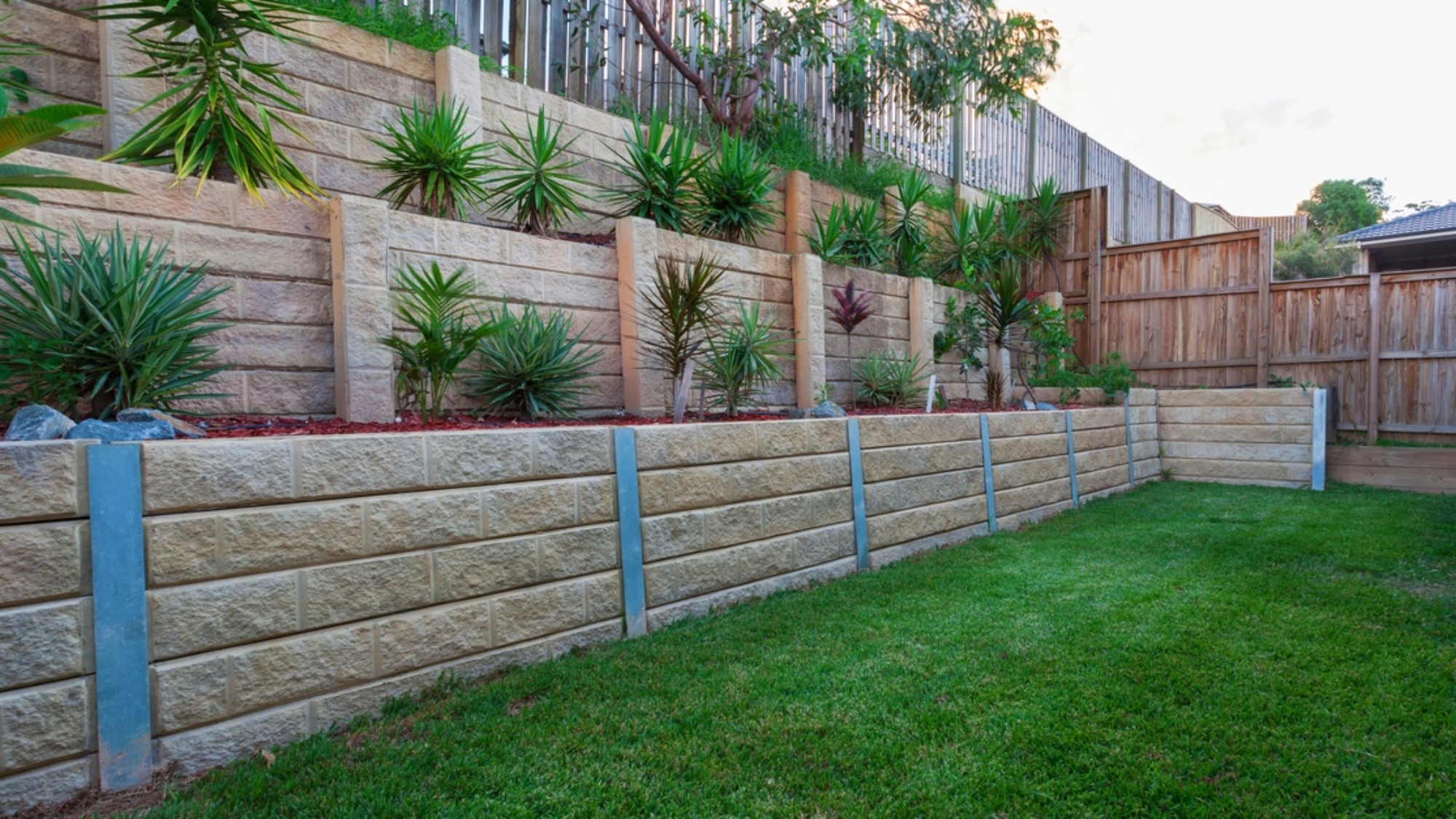 A multi-level retaining wall constructed with light-colored stones. There are plants strategically placed in each tier.