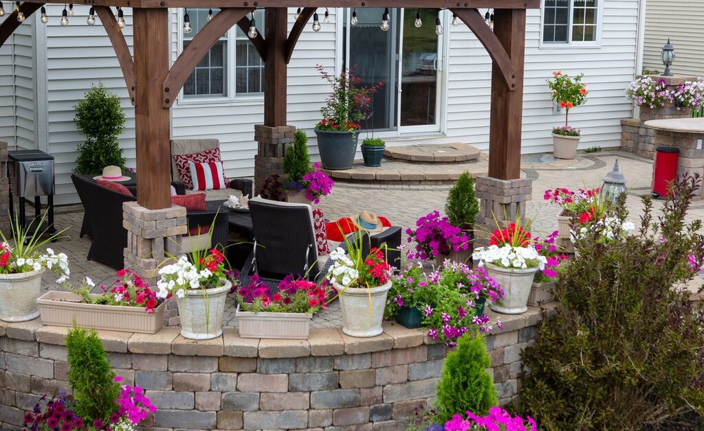 A retaining wall made out of multi-color stones. There are plants set along the top of the wall, which runs around the patio.