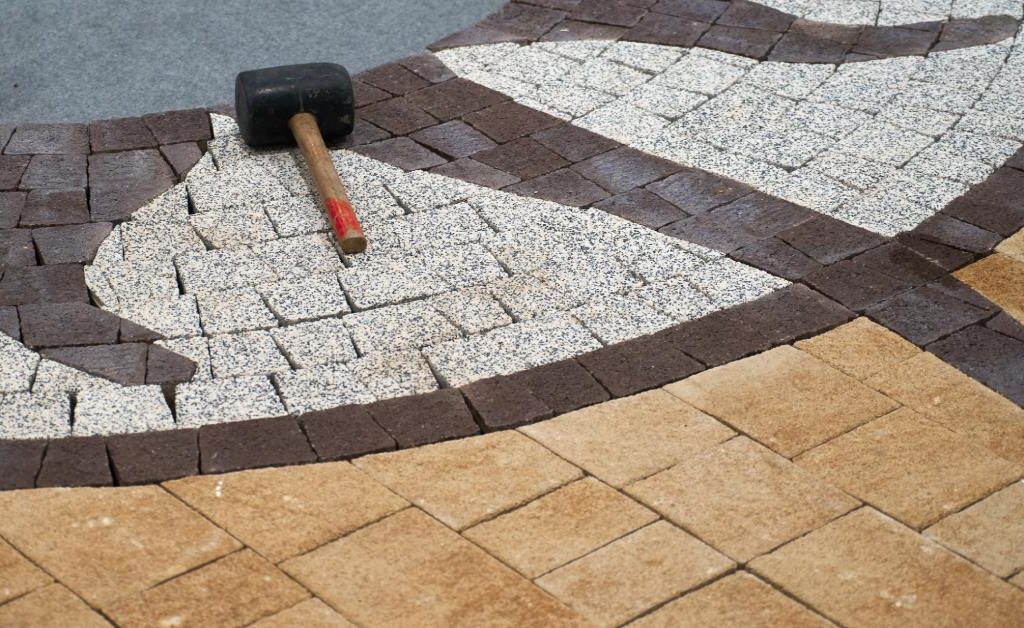 A hammer lying on a floor made of colored tiles. The tiles include a sun-shaped pattern in their layout.