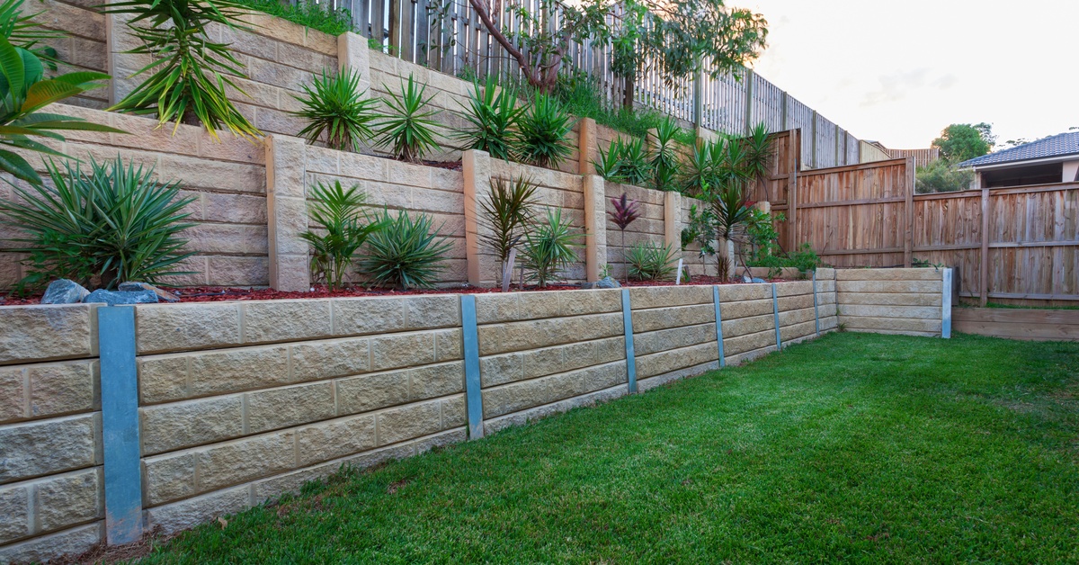 A multi-level retaining wall constructed with light-colored stones. There are plants strategically placed in each tier.